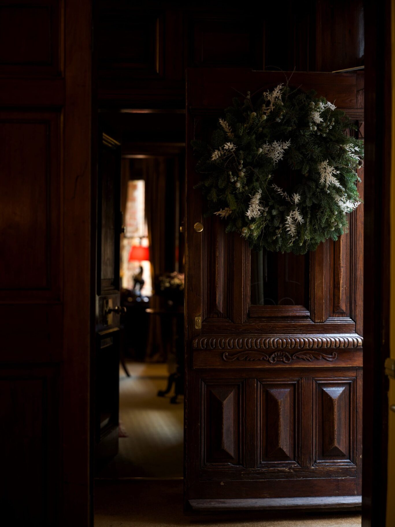 Carved wooden door at The Rookery in Clerkenwell decorated with a large evergreen Christmas wreath.